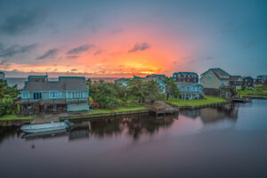 Outer Banks Wedding Accommodations. The sun sets behind a row of waterfront cottages on Hatteras Island, NC.